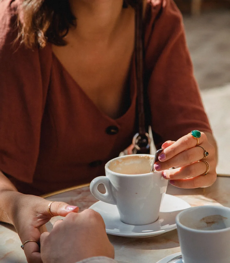 Two people sharing coffee across a cafe table during a supportive conversation