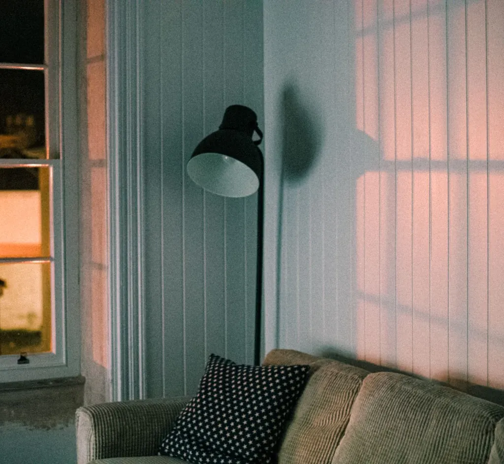 A warm living room with a soft couch and a floor lamp casting gentle light