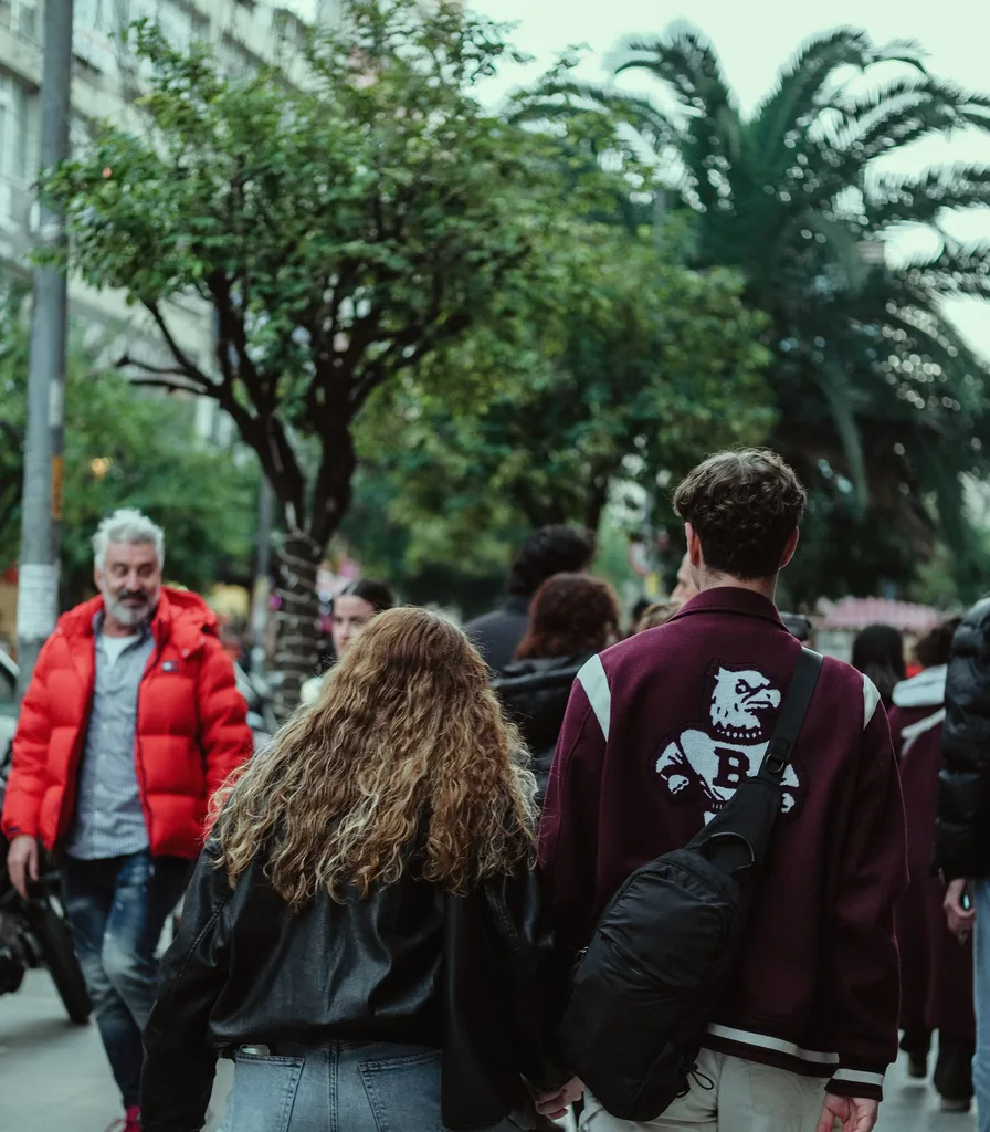 People walking together along a palm-lined street, seen from behind