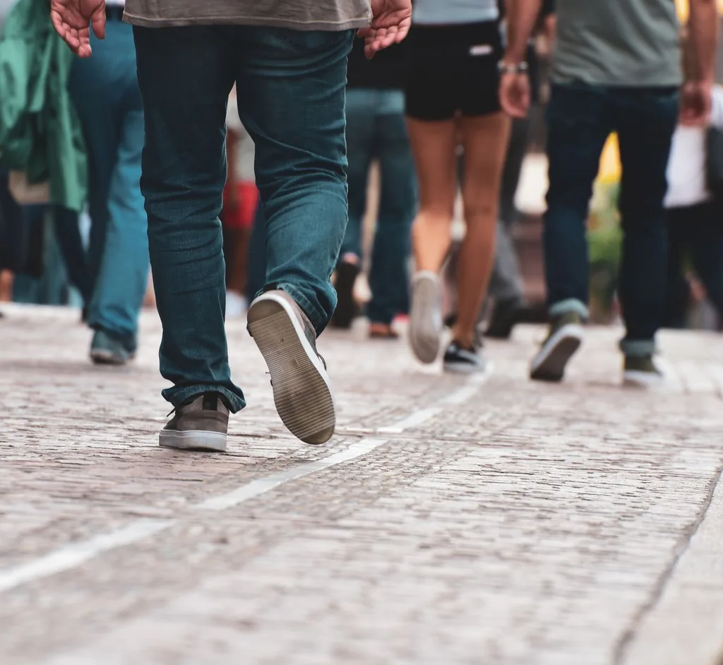 A diverse group of people walking together along a cobblestone street