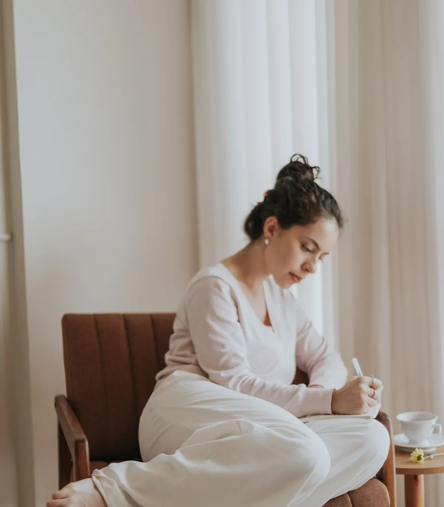 Woman writing in a journal at home during a quiet moment of reflection