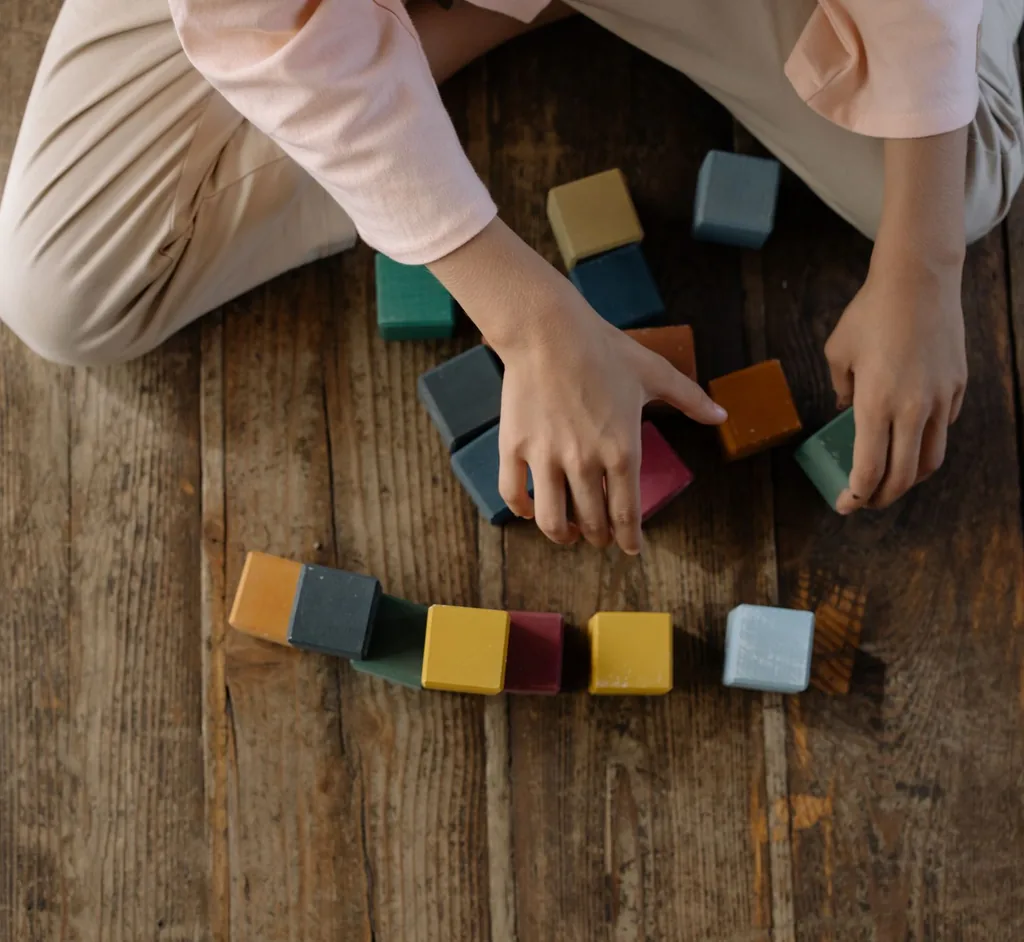 Child arranging colorful blocks during play-based ADHD and autism support