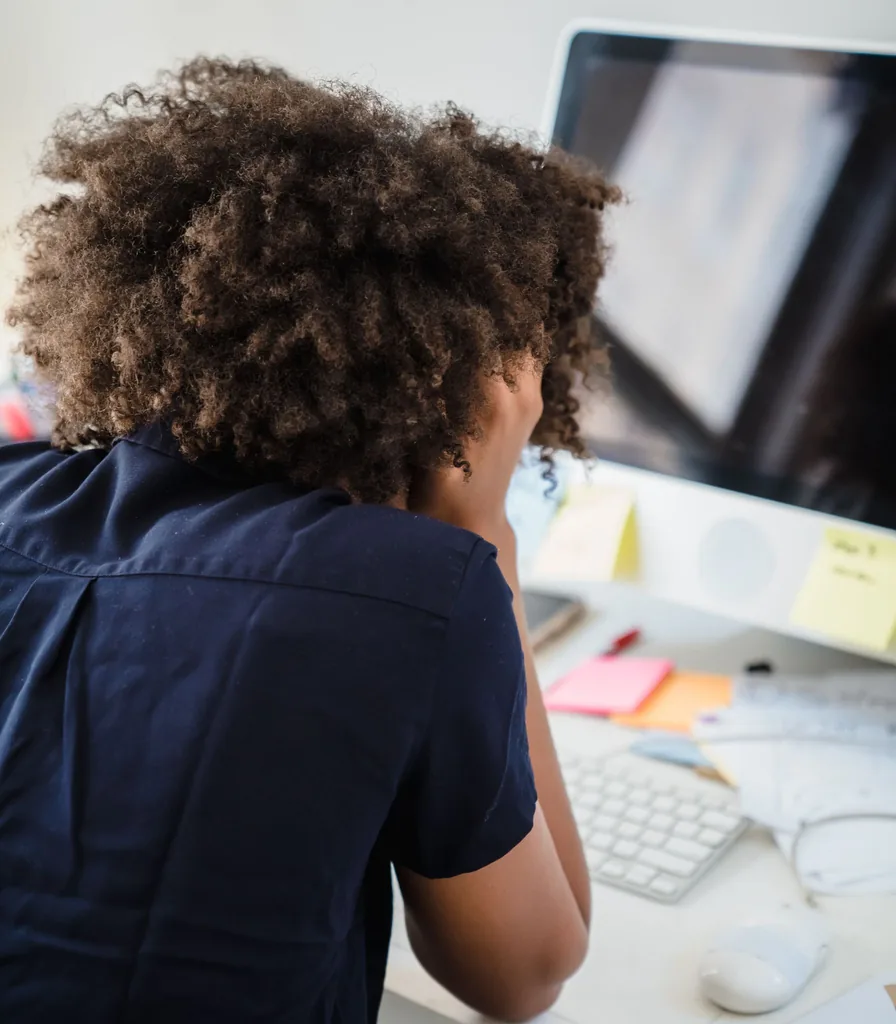 Woman resting her head in her hands at a desk while feeling overwhelmed