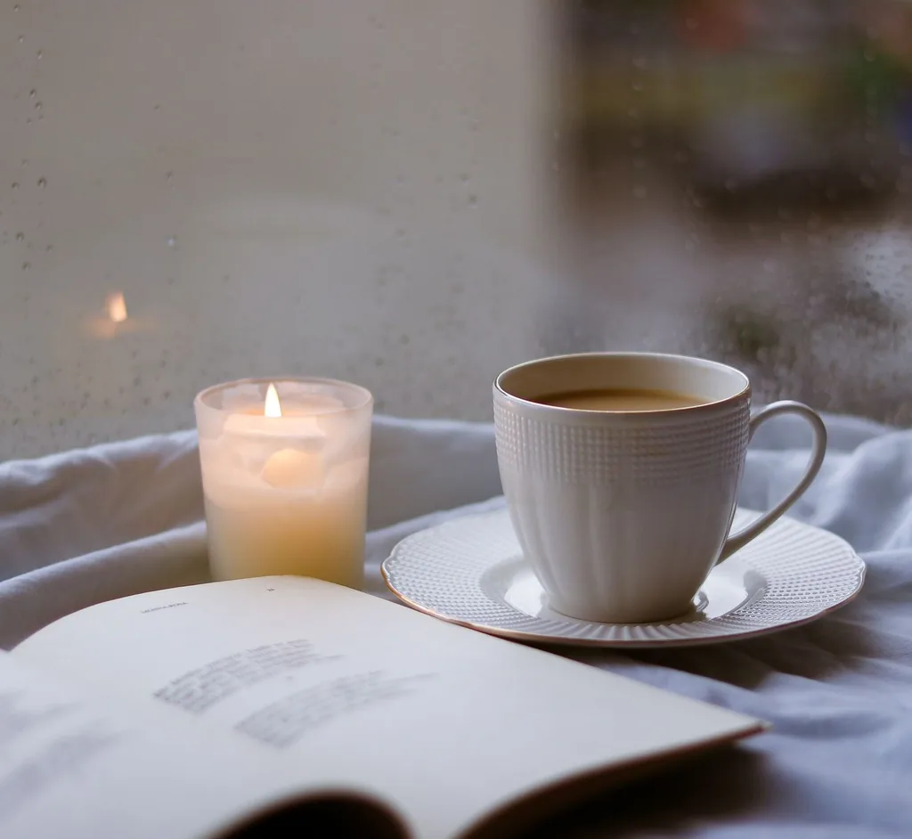 A cup of coffee, a candle and an open book in a restful corner