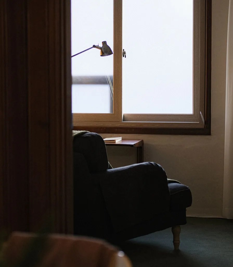 A comfortable armchair beside a window in a peaceful, uncluttered room