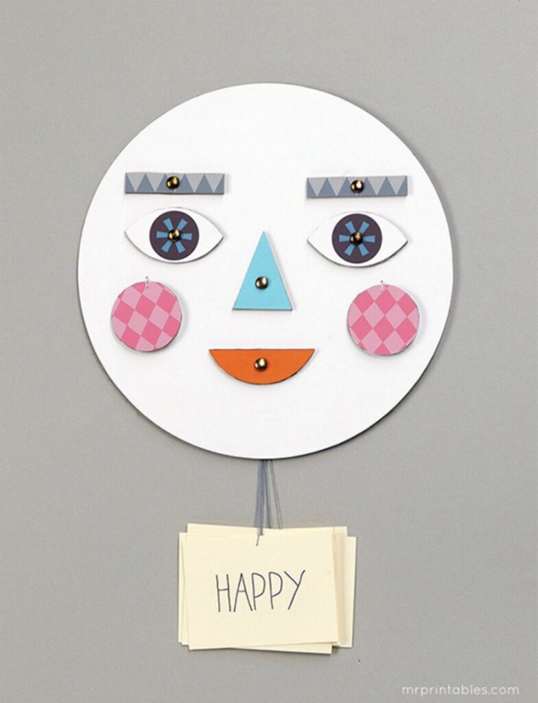 A paper face craft with movable eyes, eyebrows and mouth, with a HAPPY emotion card hanging below